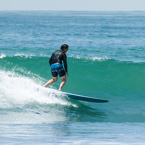 Goofy foot surfer going left on a greenish blue wave